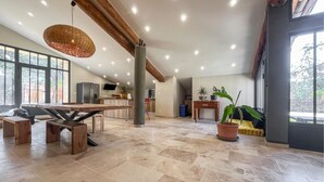 Un salón amplio con una gran mesa de madera, una lámpara colgante y una planta en maceta.