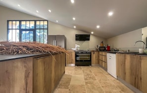 A modern kitchen with wooden cabinets, a built-in oven, and a large window.