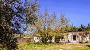 Un bâtiment rustique avec un jardin, une balançoire et un ciel d’un bleu éclatant.