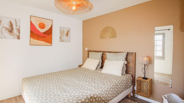 Une chambre à coucher avec un lit, une table de chevet, une lampe et des œuvres d’art murales.