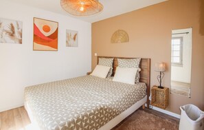 Quarto com cama, mesa de cabeceira, abajur e quadros nas paredes.