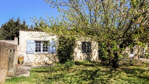 Un bâtiment rustique doté d’une petite fenêtre et d’une porte, entouré de verdure.