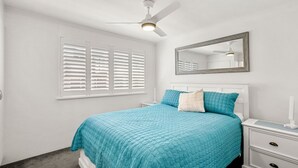 A bedroom with a bed, a nightstand, a mirror, and a ceiling fan. - Ocean Breeze Unit 10, 42 King Street, Kings Beach (Kings Beach)
