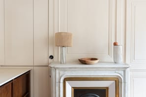 A room with a fireplace, a wooden bowl on the mantel, a lamp, and a vase. - Le Splendide - Au cœur du 6ème arrondissement (Lyon)