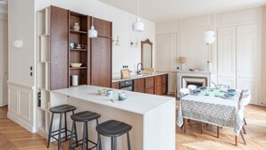 Eine moderne Küche mit Kochinsel, Barhocker, Holzschränken und einem Essbereich mit Tisch für vier Personen.