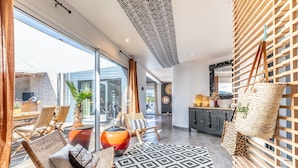 A modern interior with wicker furniture, a patterned rug, and a large vase. - Villa Mindoya - Villa pour 10, piscine chauffée (Labenne)