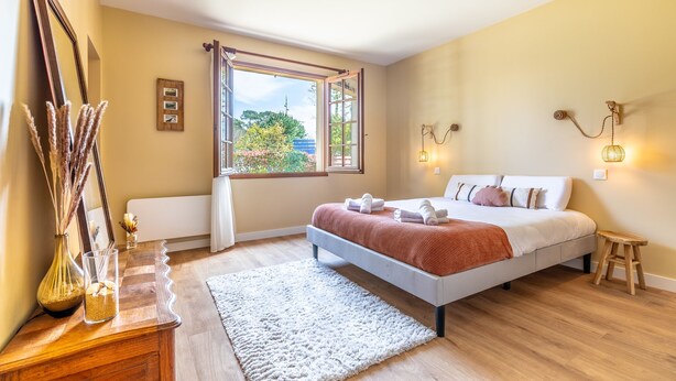 Une chambre à coucher avec un lit, une table de chevet, une lampe et une fenêtre.