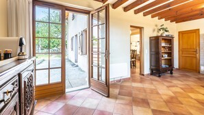 Une pièce spacieuse avec un plafond en bois, une grande porte-fenêtre coulissante donnant sur l’extérieur, un meuble en bois et un sol carrelé.