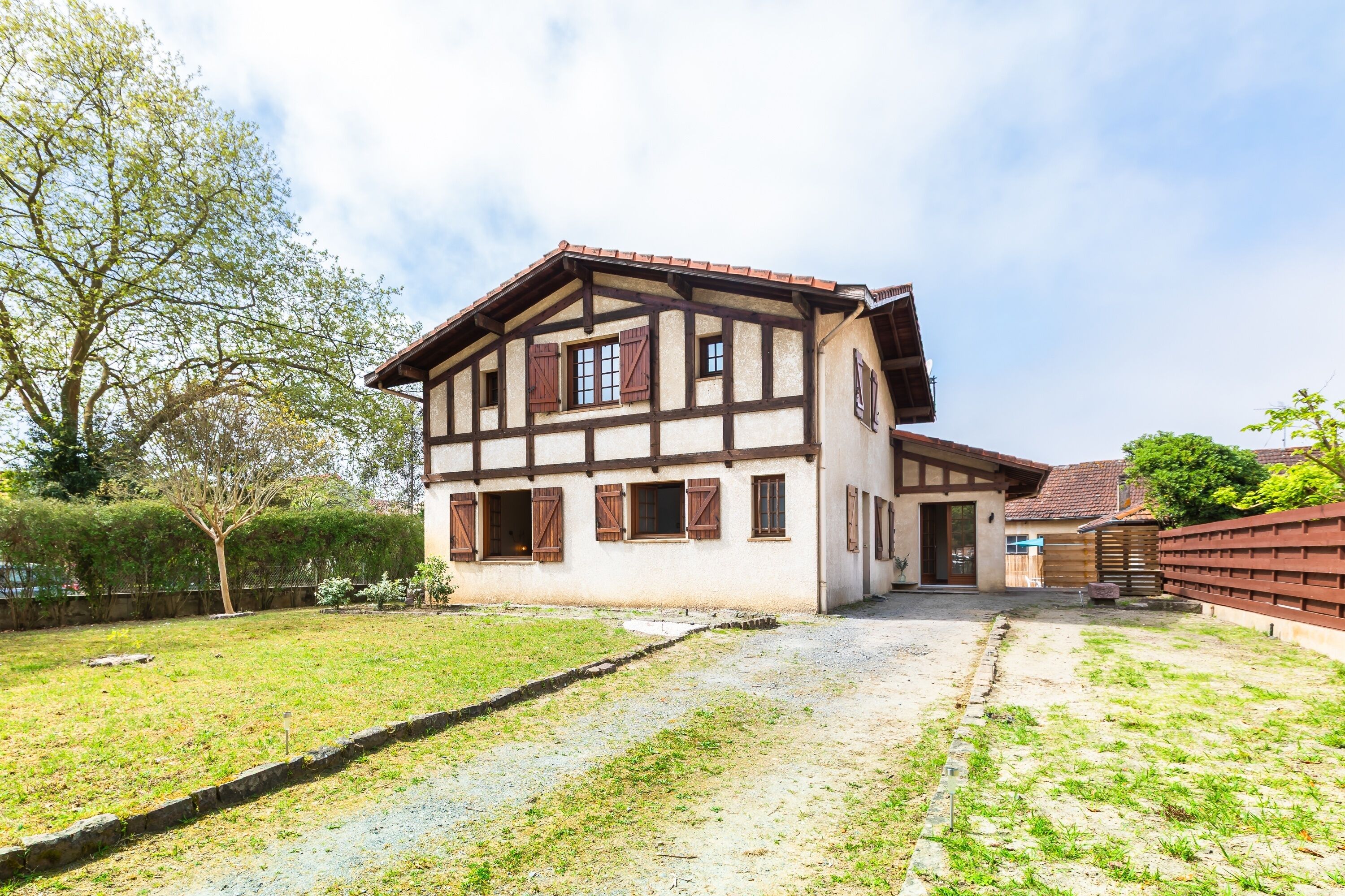 A traditional half-timbered house with a gravel driveway and a small garden.