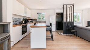 Une cuisine moderne avec un îlot central, un coin repas avec une chaise et un canapé offrant une belle vue.