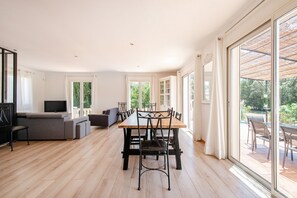 A spacious living area with a dining table, chairs, a sofa, and a TV. - La Maison du Néflier - Avec Piscine Privée (Tavernes)