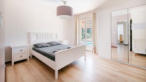 Une chambre à coucher avec un lit, des tables de chevet, une armoire et un grand miroir.