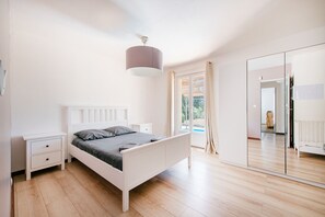Ein Schlafzimmer mit Bett, Nachttischen, einem Kleiderschrank und einem großen Spiegel.