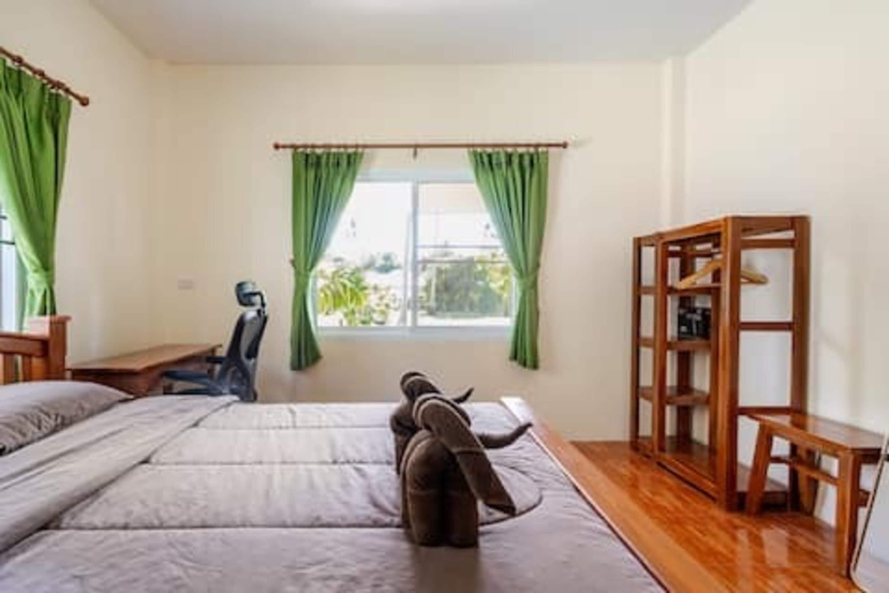 A room with a bed, a desk, and a window with curtains.