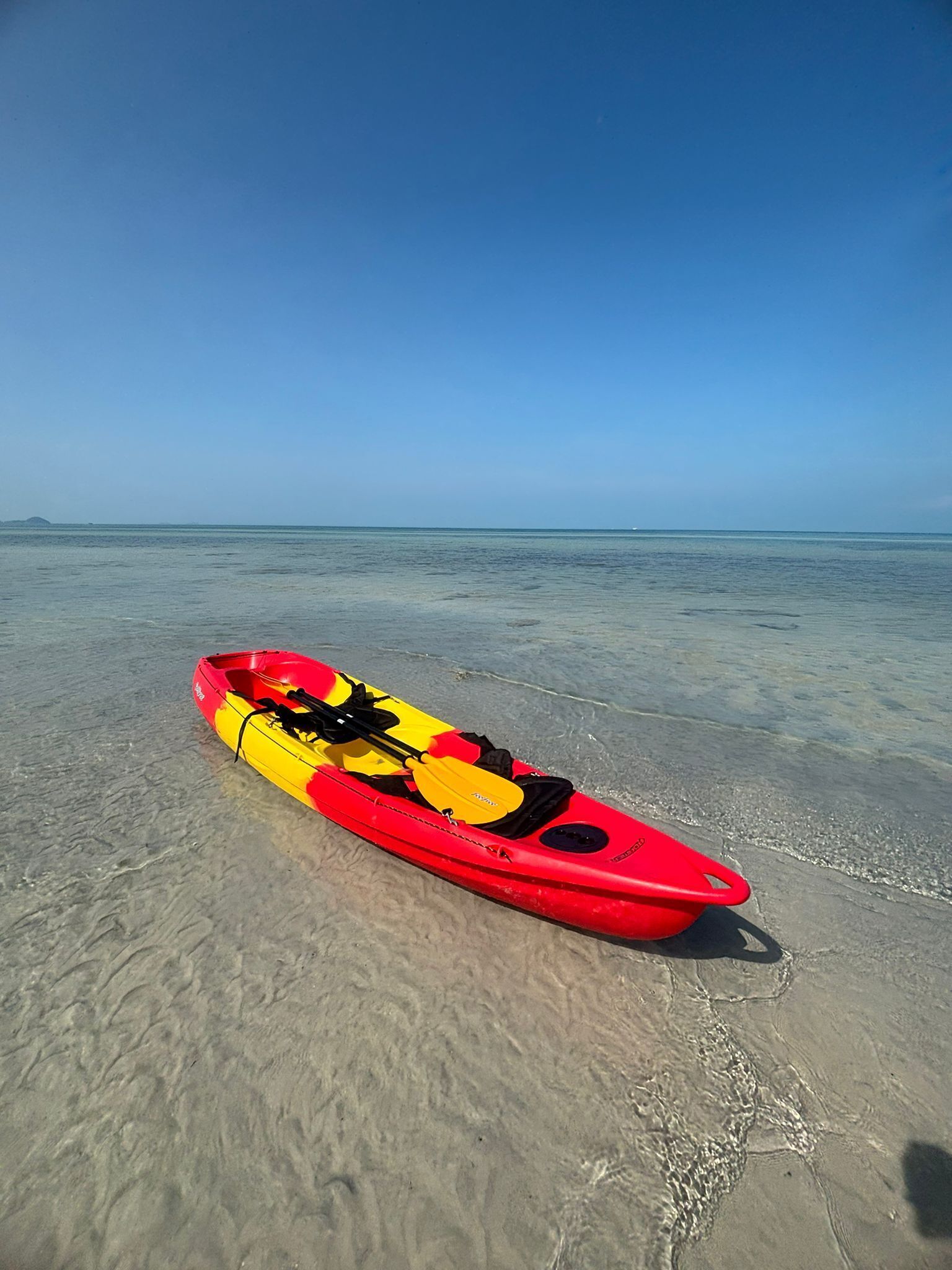 Un kayak rosso con dettagli gialli su una spiaggia sabbiosa.