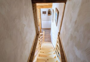 A wooden staircase leading to a room with a white radiator and a key hanging on the wall. - CASA-Marguerite centre St Véran cosy 3ch (Molines-en-Queyras)