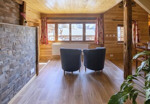 A wooden cabin interior with a stone wall, two chairs, a radiator, and a window with a view of mountains. - CASA-Marguerite centre St Véran cosy 3ch (Molines-en-Queyras)