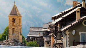 Ein historisches Dorf mit Steinhäusern, hölzernen Balkonen und einem Kirchturm.