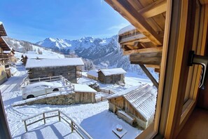 A wooden cabin with a view of snow-covered mountains and a car parked outside. - CASA-Marguerite centre St Véran cosy 3ch (Molines-en-Queyras)