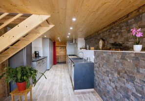 A modern kitchen with a stone backsplash, wooden ceiling, and a central island. - CASA-Marguerite centre St Véran cosy 3ch (Molines-en-Queyras)