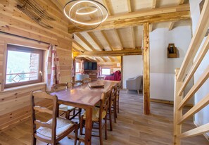 Un interior de madera con una mesa de comedor, sillas, una escalera y una zona de cocina.