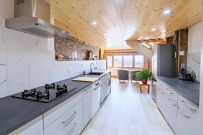 A modern kitchen with a gas stove, a sink, and a refrigerator. - CASA-Marguerite centre St Véran cosy 3ch (Molines-en-Queyras)