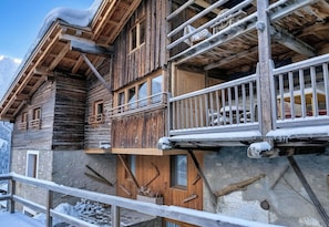 A wooden chalet with a balcony, stone walls, and a wooden door. - CASA-Marguerite centre St Véran cosy 3ch (Molines-en-Queyras)