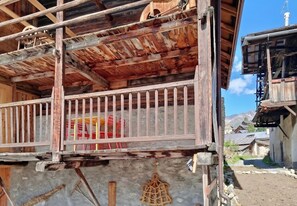 Un balcon en bois avec une rambarde en métal, un plancher en béton et une corde suspendue au plafond.
