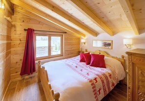 A wooden cabin bedroom with a bed, red curtains, a window, and a wall-mounted lamp. - CASA-Marguerite centre St Véran cosy 3ch (Molines-en-Queyras)