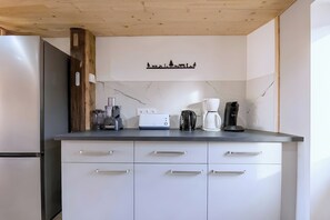 A kitchen with a wooden ceiling, white cabinets, and a coffee maker on the counter. - CASA-Marguerite centre St Véran cosy 3ch (Molines-en-Queyras)