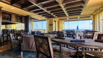 A restaurant with high ceilings, patterned upholstery, and large windows offering a view.