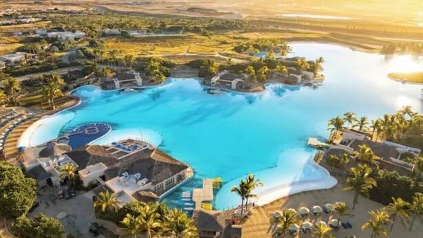 Ein Resort mit einem großen zentralen Pool, mehreren kleineren Pools und einem Strandbereich.