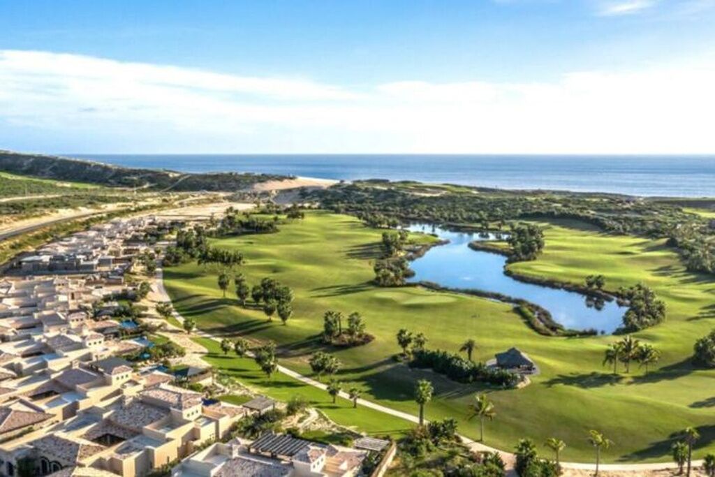 A golf course with a water feature, surrounded by residential buildings.