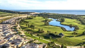 Ein Golfplatz mit Wasserelement, umgeben von Wohnhäusern.