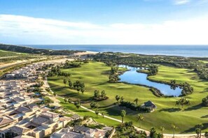 Un parcours de golf agrémenté d’un plan d’eau, entouré de bâtiments résidentiels.