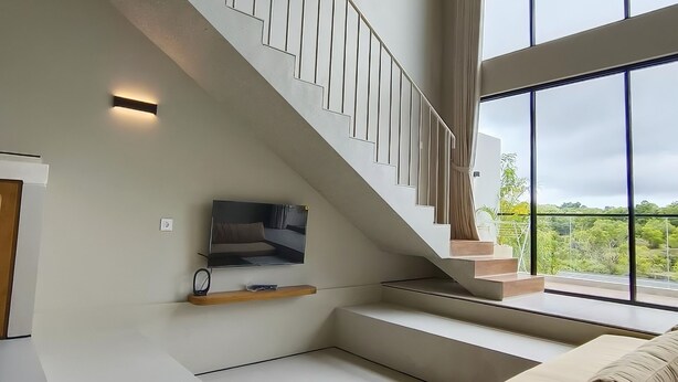 Ein modernes Interieur mit einer Treppe, einem Sofa und einem an der Wand befestigten Fernseher.