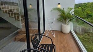 Ein Balkon mit Holzboden, einem Blumentopf, einem Metallstuhl und einem weißen Wäscheständer.