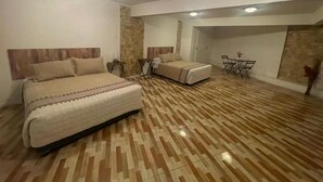 Une chambre avec un grand lit, un petit canapé, une table à manger et un mur décoratif en pierre.