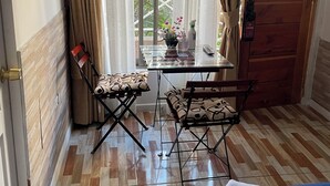 Une chambre avec un lit, une table et des chaises, un téléviseur et une vue sur la verdure.