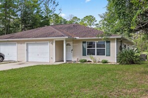 A single-story house with a garage, a front porch, and a well-maintained lawn. - Spacious vacation home near beach with baby friendly amenities (Palm Coast)