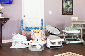 A room with a baby changing station, a white door, a small table with a chair, and a painting on the wall. - Spacious vacation home near beach with baby friendly amenities (Palm Coast)