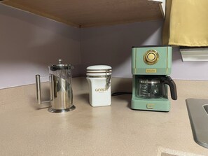 A kitchen counter with a coffee maker, a French press, and a container labeled 'GEVALIA KAFÉ'.