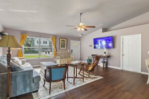 A living room with a sofa, chairs, a TV, and a ceiling fan. - Spacious vacation home near beach with baby friendly amenities (Palm Coast)