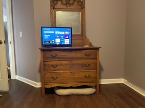 A wooden dresser with a television on top displaying a streaming service interface.