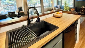 Une cuisine moderne dotée d’un plan de travail en bois, d’un évier noir et d’une cuisinière intégrée.