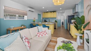 A modern living room with a sofa, a coffee table, and a dining area with a kitchen in the background. - Stylish 5min Downtown Orlando (Orlando)
