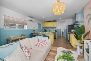 A modern living room with a sofa, a coffee table, and a dining area with a kitchen in the background. - Stylish 5min Downtown Orlando (Orlando)