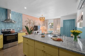 A modern kitchen with a stainless steel range hood, a granite countertop, and a built-in oven. - Stylish 5min Downtown Orlando (Orlando)