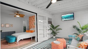 A modern bedroom with a bed, a ceiling fan, a TV, and a large window. - Stylish 5min Downtown Orlando (Orlando)
