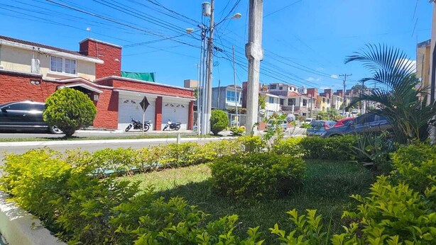 A residential street with houses, parked cars, and a well-maintained garden. - Casa Nimajay (Guatemala City)